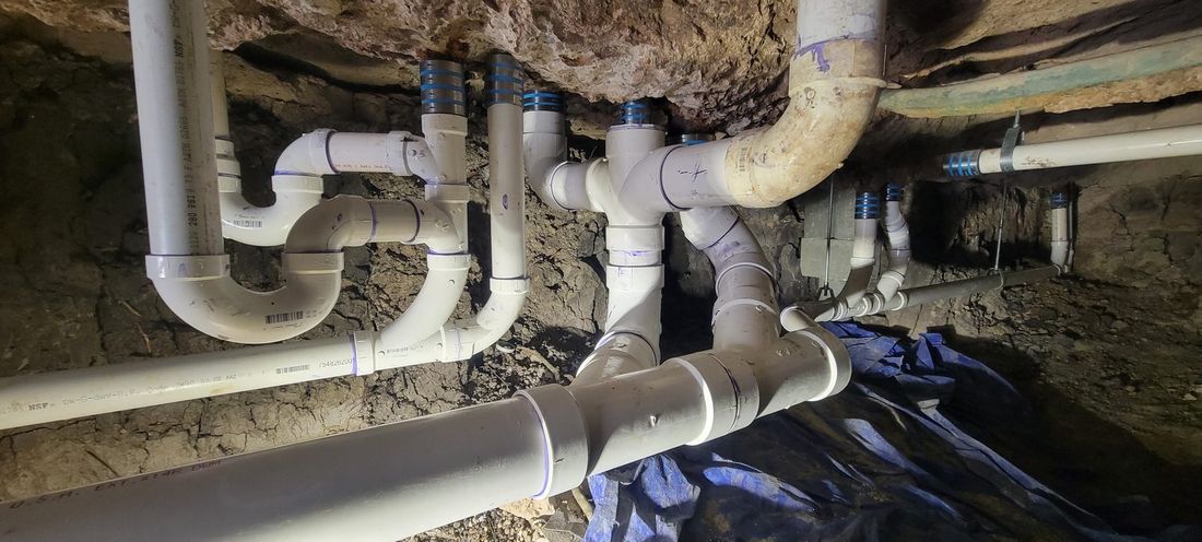 Under-slab PVC drain, waste and vent piping network beneath a building