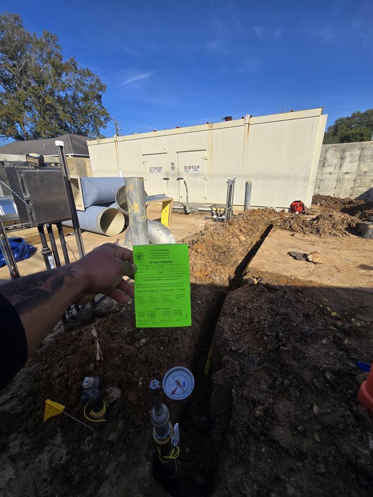City of Houston plumbing inspection tag marked Approved, held over a finished trench