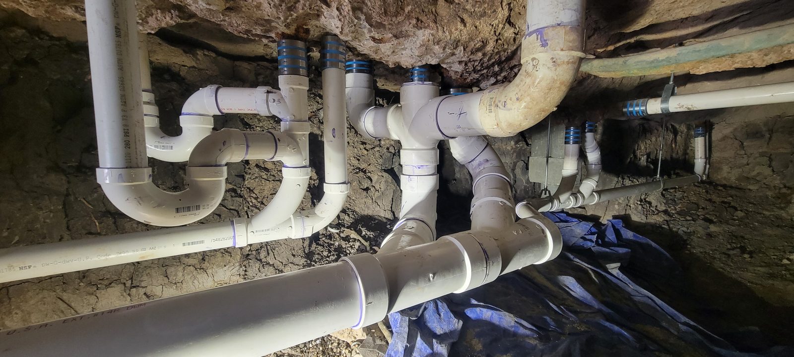 Under-slab PVC drain, waste and vent piping network fit together beneath a building
